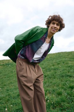 Gündelik giysiler içindeki öğrenci yemyeşil arazide yürüyor, bulutlu gökyüzünün altında gülümsüyor..