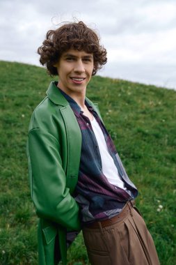 Neşeli bir öğrenci yemyeşil bir alanda geziniyor, gençlik cazibesini ve rahat stilini sergiliyor..