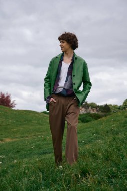 Yakışıklı öğrenci açık havada sakin bir anı kucaklayarak, canlı yeşil bir manzarada geziniyor..