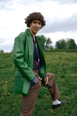 Yakışıklı öğrenci yemyeşil bir arazide geziniyor, açık havanın güzelliğini kucaklıyor..
