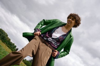 Yeşil ceketli bir öğrenci gri gökyüzünün altında öylesine geziniyor..