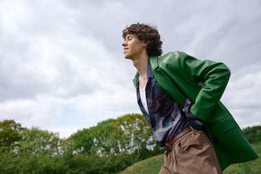 Yakışıklı genç adam yemyeşil bir arazide geziniyor, huzurlu bir günün tadını çıkarıyor..