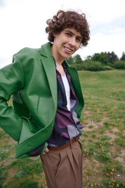 Şık yeşil ceketli genç adam yemyeşil alanda geziniyor..