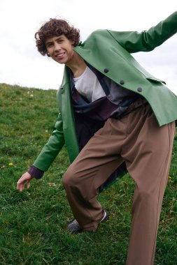 Yakışıklı bir öğrenci yeşilliklerle çevrili şık kıyafetlere güvenerek dışarı çıkıyor..