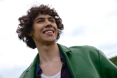 Tarz sahibi genç bir adam, doğa ve yumuşak bulutlar arasında mutluluk saçarak güvenli bir şekilde dolaşır..