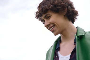 Neşeli genç bir öğrenci açık hava ortamında parlak bir gülümsemeyle geziniyor..