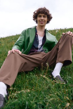 Yakışıklı öğrenci yemyeşil çimenlikte gezintiye çıkıyor, şık kıyafetlerini sergiliyor..