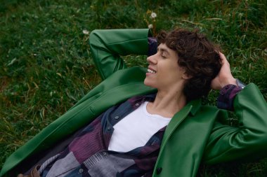 Genç ve yakışıklı bir öğrenci çimenlerde uzanıyor, doğanın sakinliğini kucaklıyor..
