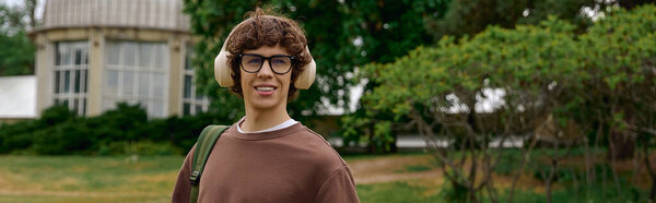 Красивый молодой человек счастливо прогуливается на открытом воздухе, одетый в теплые зимние аксессуары и рюкзак.