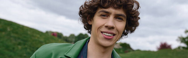 Красивый молодой студент неторопливо прогуливается на свежем воздухе, наслаждаясь природой и спокойствием.