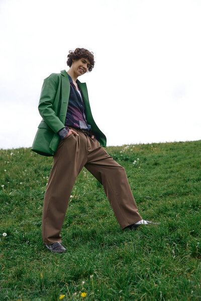 Очаровательный молодой человек прогуливается по зеленой траве, наслаждаясь спокойствием природы и свежим воздухом.