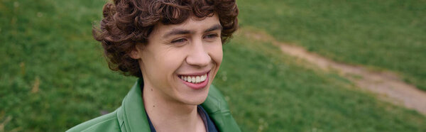 Красивый молодой человек прогуливается по зеленому парку, наслаждаясь природой и свежим воздухом.