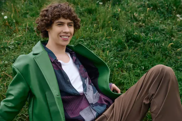 Genç bir adam, canlı yeşil bir ceketle doğa güzelliğinde dolaşırken rahatlar..