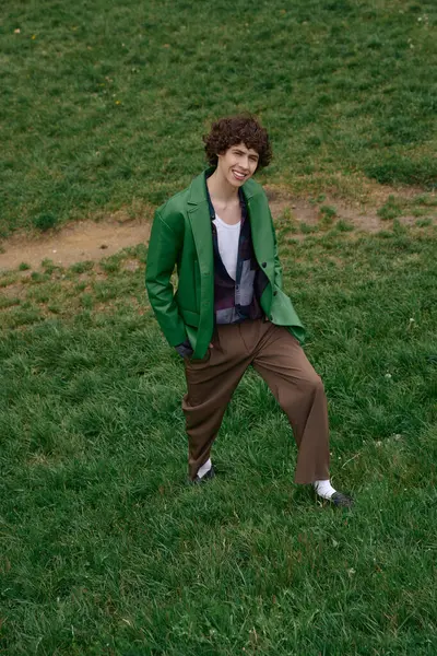 Genç bir adam, güneşli bir günde yeşil çimlerde dolaşırken çevresini inceliyor..