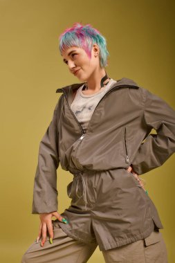 Yaratıcı genç bir kadın renkli kısa saçlarını ve şık kıyafetlerini parlak bir stüdyoda sergiliyor..