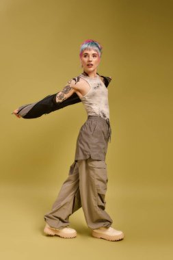 Genç bir kadın canlı bir stüdyoda poz verirken renkli ve kısa saçlarını sergiliyor..