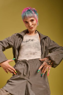 Neşeli bir pozla, benzersiz giyinmiş genç bir kadın tarzını parlak bir arkaplanda ifade eder..