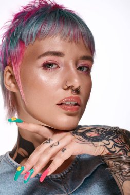 Kısa, renkli saçları olan genç bir kadın stüdyoda poz veriyor, eşsiz tarzını sergiliyor..