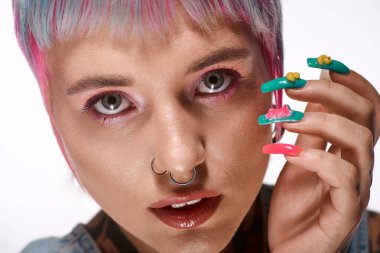 Kısa, renkli saçlı genç bir kadın stüdyoda yaratıcı bir şekilde poz veriyor, benzersiz görünümünü vurguluyor..