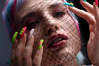 Renkli kısa saçlı genç bir kadın stüdyoda yaratıcı bir şekilde poz veriyor..