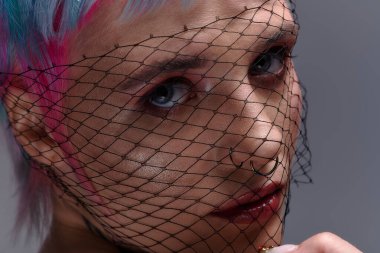 Kısa, canlı saçlı genç bir kadın yaratıcı bir poz veriyor, modern gençlik kültürünü somutlaştırıyor..