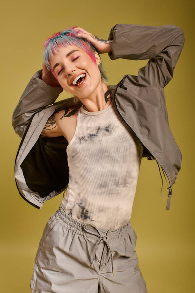 Young woman with short, vibrant hair radiates joy while posing in a studio space.