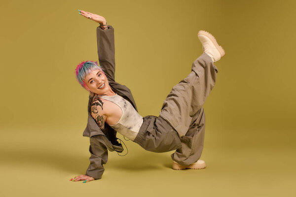 Молодая женщина с яркими короткими волосами принимает динамичную позу, излучая счастье в студии.