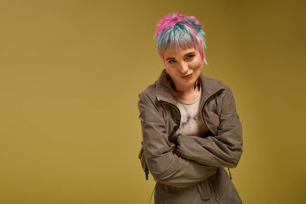 A young woman displays her unique style with vibrant hair colors in a studio space.