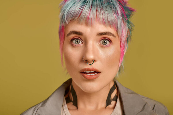 A young woman showcases her colorful short hair against a vivid background in a studio.