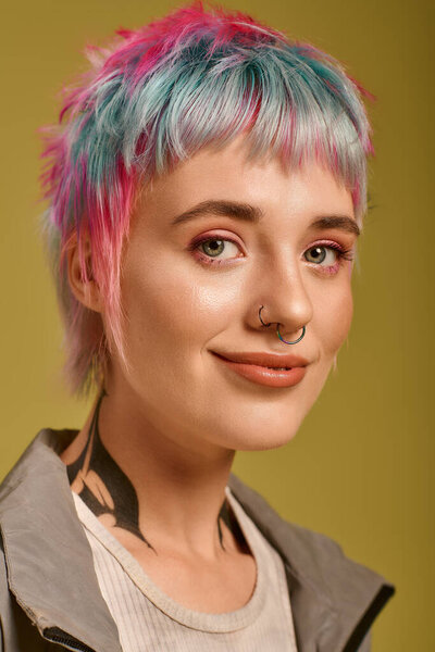 Молодая женщина с яркими короткими волосами уверенно улыбается в студии, демонстрируя свою красоту.