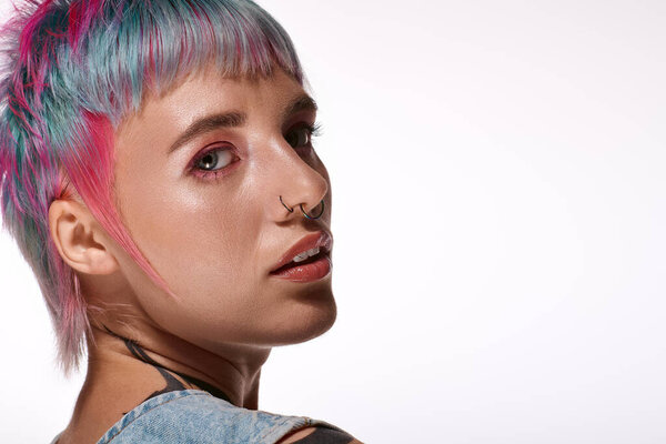 Молодая женщина с короткими, красочными волосами источает уверенность в яркой обстановке студии.