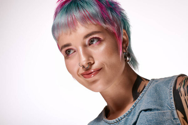 A young woman with short dyed hair smiles joyfully in a bright studio setting.