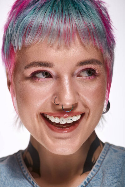 Веселая молодая женщина с короткими, красочными волосами ярко улыбается в модной студии.