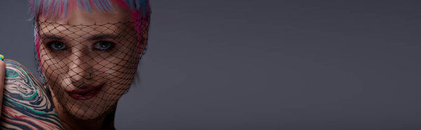 A young woman showcases her colorful, short hair and unique fashion in a cozy studio space, banner