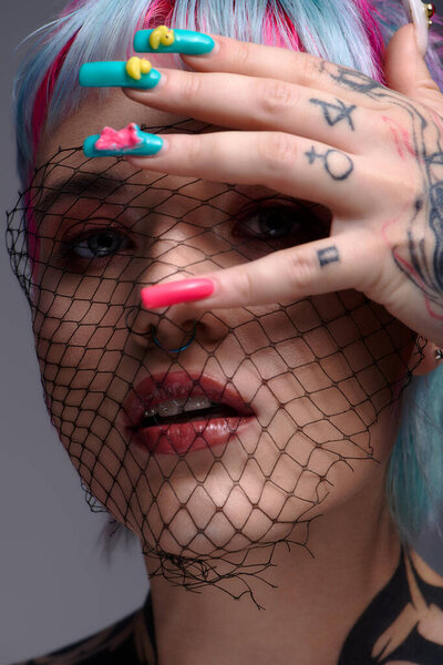 Молодая женщина демонстрирует свои яркие, окрашенные волосы и художественные ногти в творческой студии.