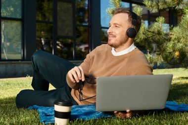 Genç bir adam, bir üniversite öğretmeni, dışarıda laptopu ve kahvesiyle ders çalışmaktan hoşlanıyor..