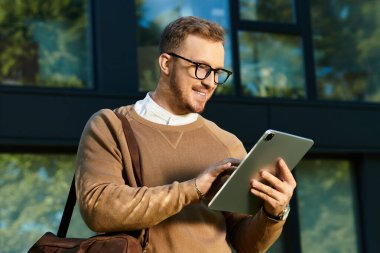 Genç bir öğretmen modern bir binanın önünde tablet kullanırken gülümser..