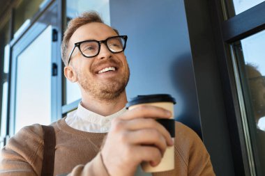 Genç bir adam, bir üniversite öğretmeni, kahve molası veriyor, rahat bir ortamda mutlu bir şekilde gülümsüyor..