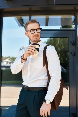 Genç bir erkek eğitimci, çağdaş bir üniversite binasının önünde kendinden emin bir şekilde kahve yudumluyor..