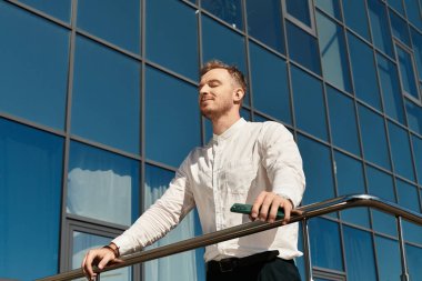 Genç bir öğretmen güven içinde bir üniversite binasının önünde duruyor ve huzurlu bir anın tadını çıkarıyor..