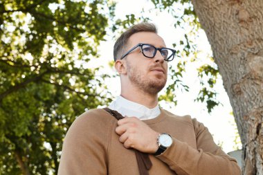 Genç bir adam bir ağacın altında duruyor, doğada bir üniversite öğretmeni olarak geçirdiği günü yansıtıyor..