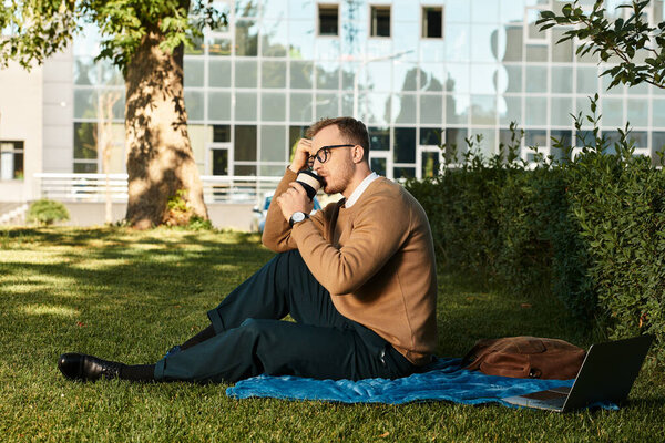 A young teacher sits on a blanket in a university courtyard, deep in thought and reflection.