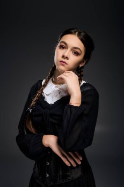 Saçları örgülü genç bir kız, Cadılar Bayramı 'nda ürkütücü bir Çarşamba karakterini somutlaştırırken gotik bir elbise giyiyor..