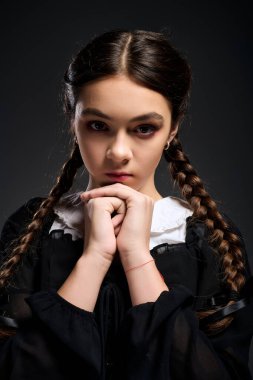 Örgülü bir kız gotik bir elbise giyer ve Cadılar Bayramı Çarşamba karakterinin özünü yakalar..