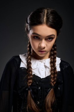 Saçları örgülü bir kız, Gotik bir elbise giyer ve çarşambayı hatırlatır..