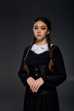 Çarşamba günü gotik bir kostüm giymiş bir kız ayakta duruyor ve Cadılar Bayramı ruhunu somutlaştırıyor..