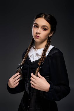 Gotik tarzda giyinmiş, örgülü bir kız Cadılar Bayramı sezonunda ürkütücü titreşimler yayıyor..