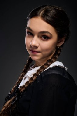 Saç örgülü bir kız, Çarşamba gotik bir elbise giyer. Cadılar Bayramı ruhunu mükemmel şekilde somutlaştırır..