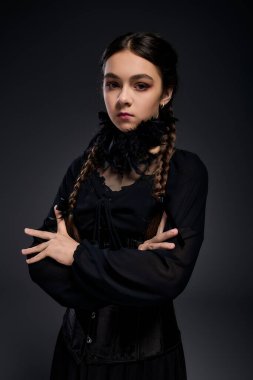 Gotik çarşamba kostümü giymiş ciddi bir kız örgü örüp Cadılar Bayramı ruhunu kucaklıyor..