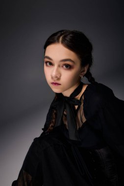 Saçları örgülü bir kız, çarşamba günü gotik bir elbise giyer ve Cadılar Bayramı ruhunu yakalar..